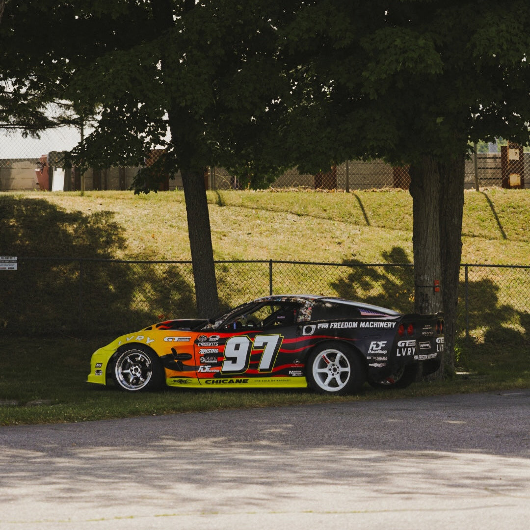 Race car with number 91 parked under a tree on a grassy area
